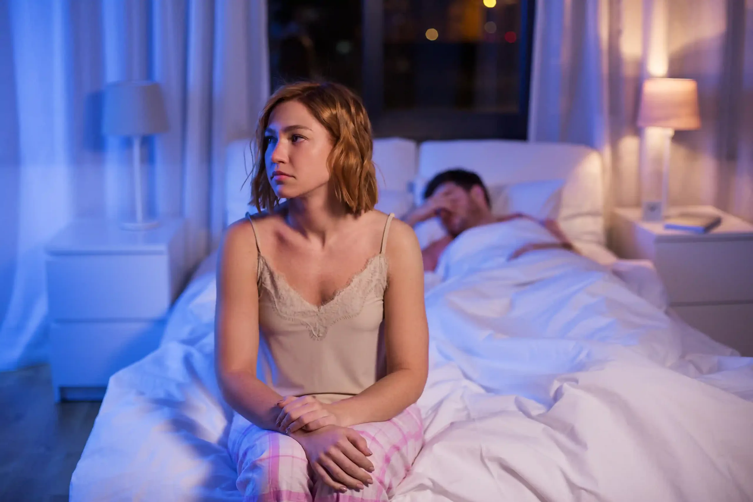 A sad women sitting on their bed when her husband rejected her sexually. Get help fixing your relationship with Marriage Helper